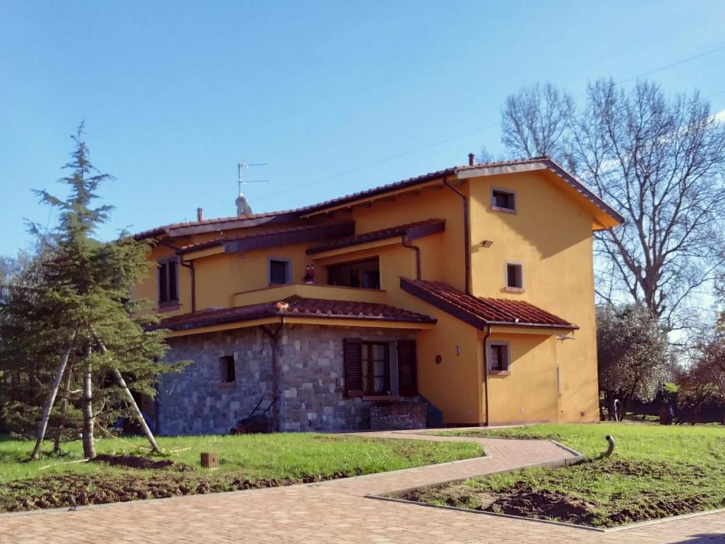 una gran casa amarilla con un camino delante de ella en Podere Pozzo Fatato en Monsummano