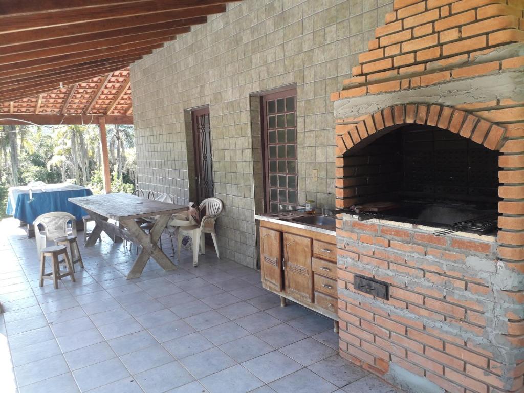 an outdoor patio with a brick oven and a table at Chácara Verava Ibiúna in Ibiúna
