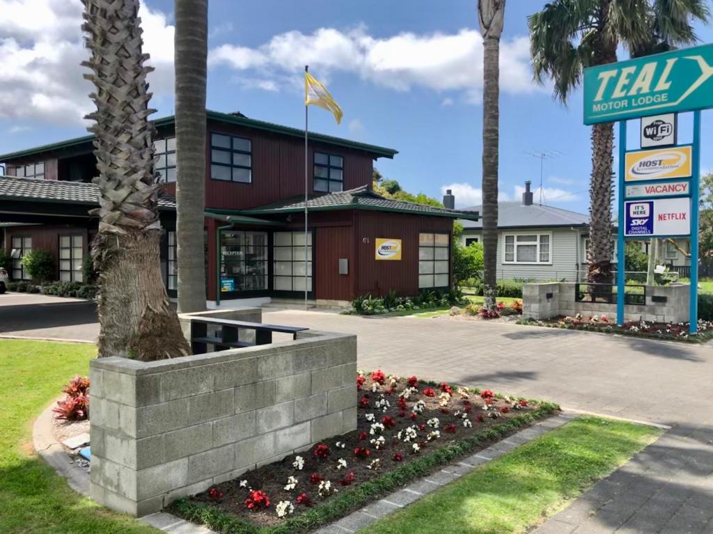 a hotel with a sign and flowers in front of it at Teal Motor Lodge in Gisborne