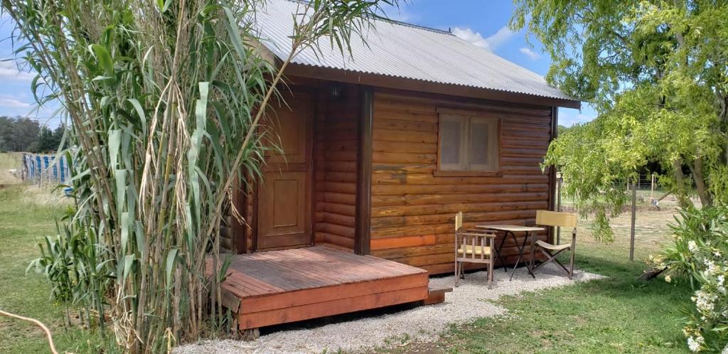 a cabin with a wooden porch and a table at Las Cabañitas in Necochea