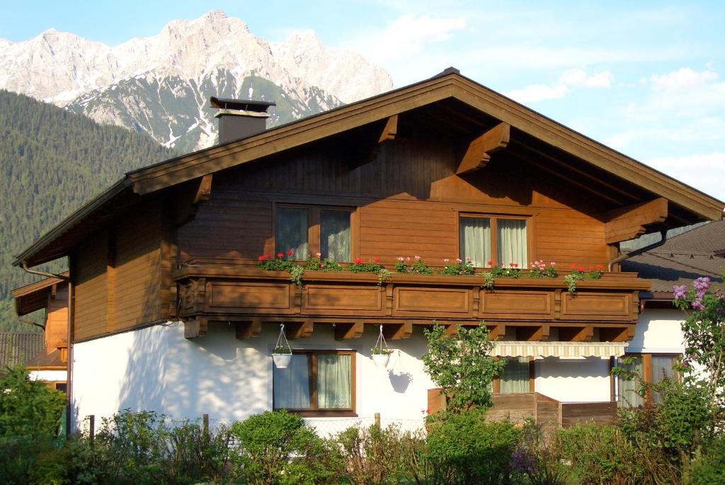 a wooden house with a balcony with flowers on it at Appartement Popelka in Saalfelden am Steinernen Meer