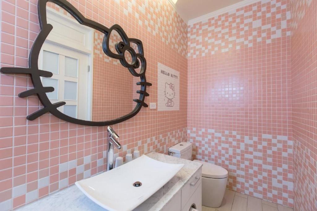 a pink tiled bathroom with a sink and a mirror at Bookline B&amp;B in Hualien City