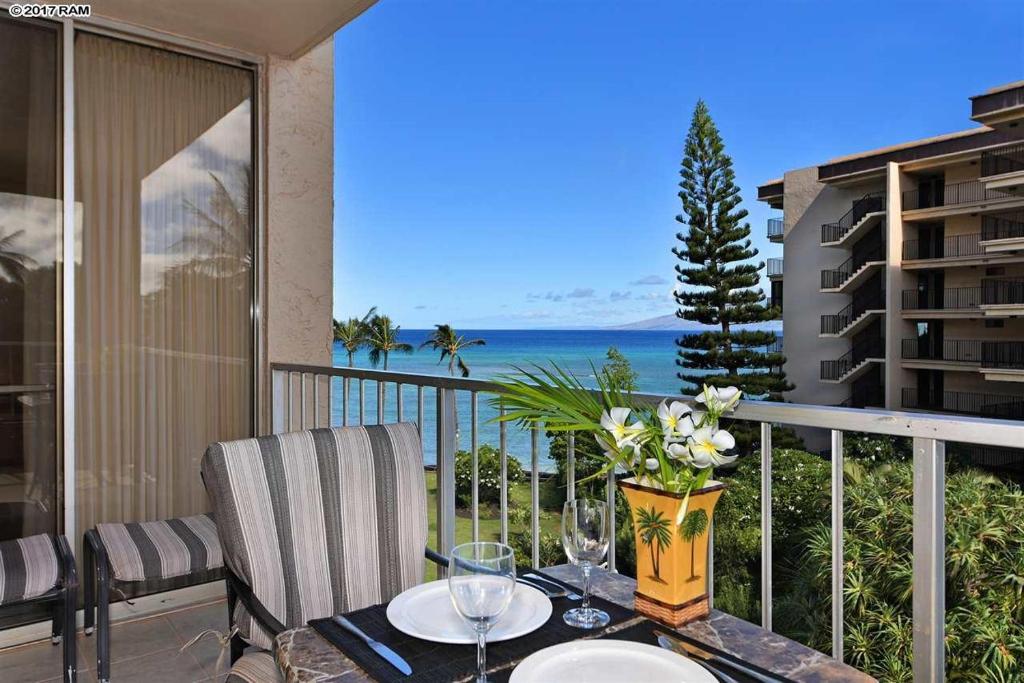 a balcony with a table with a view of the ocean at Deluxe Oceanview Maui Studio..New & Updated in Kahana