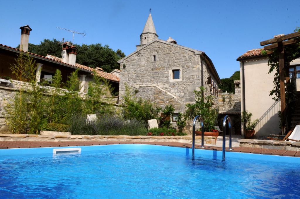an outdoor swimming pool in front of a stone building at Holiday Homes Poli Svetega Antona in Gračišće