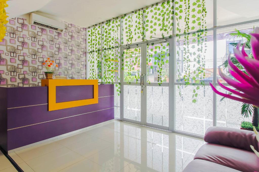 a living room with purple and purple walls and windows at RedDoorz Plus near Stasiun Bekasi in Bekasi