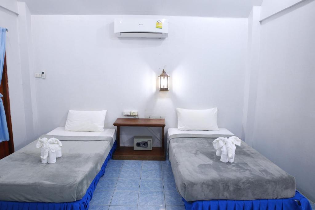 a room with two beds and a table with a lamp at Paradise Bungalows in Haad Rin