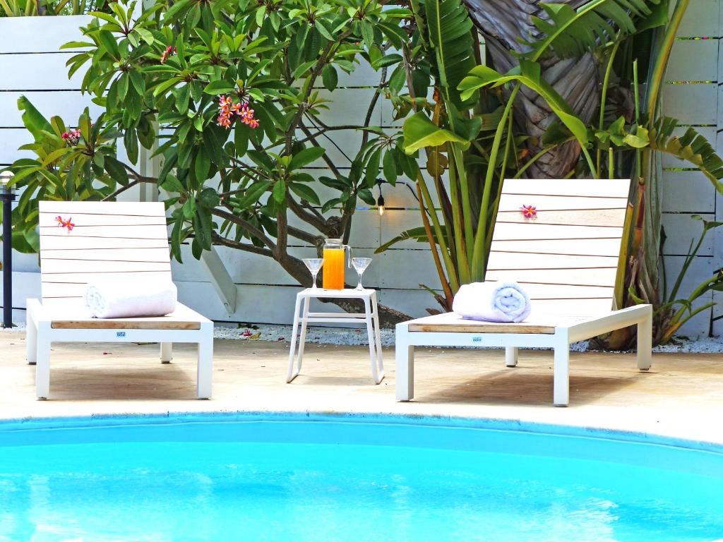 two chairs sitting next to a swimming pool at LA BOHEME, résidence de 5 appartements avec piscine, vue océan, Petite Ile in Petite Île