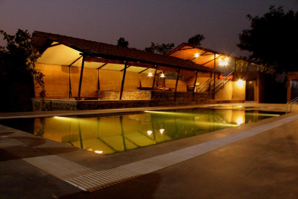a swimming pool in front of a building at night at Maati Jungle Lodge Resort Bandhavgarh in Tāla