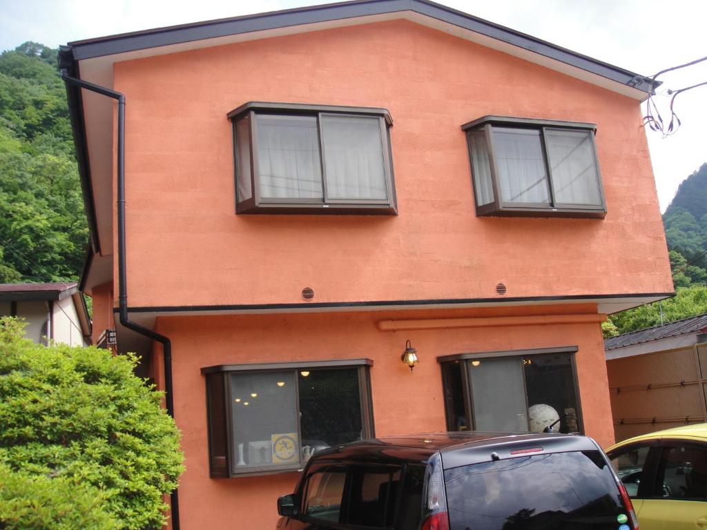 una casa roja con ventanas negras y un coche aparcado delante en Turtle Inn Nikko, en Nikko