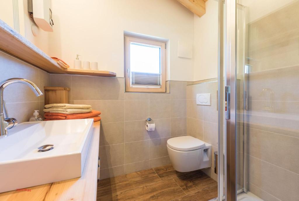 baño con lavabo y aseo y ventana en Almliesl HOLL-559, en Hollersbach im Pinzgau