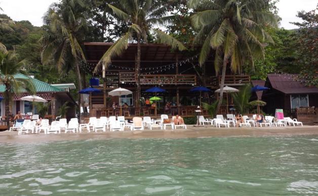 a beach with chairs and umbrellas and a restaurant at Apple Beachfront Resort in Trat