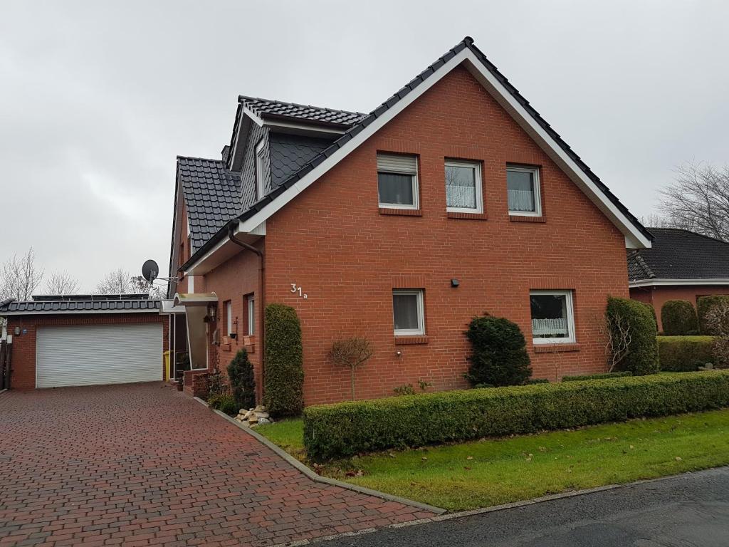 a red brick house with a brick driveway at FeWo zwischen den Deichen in Emden