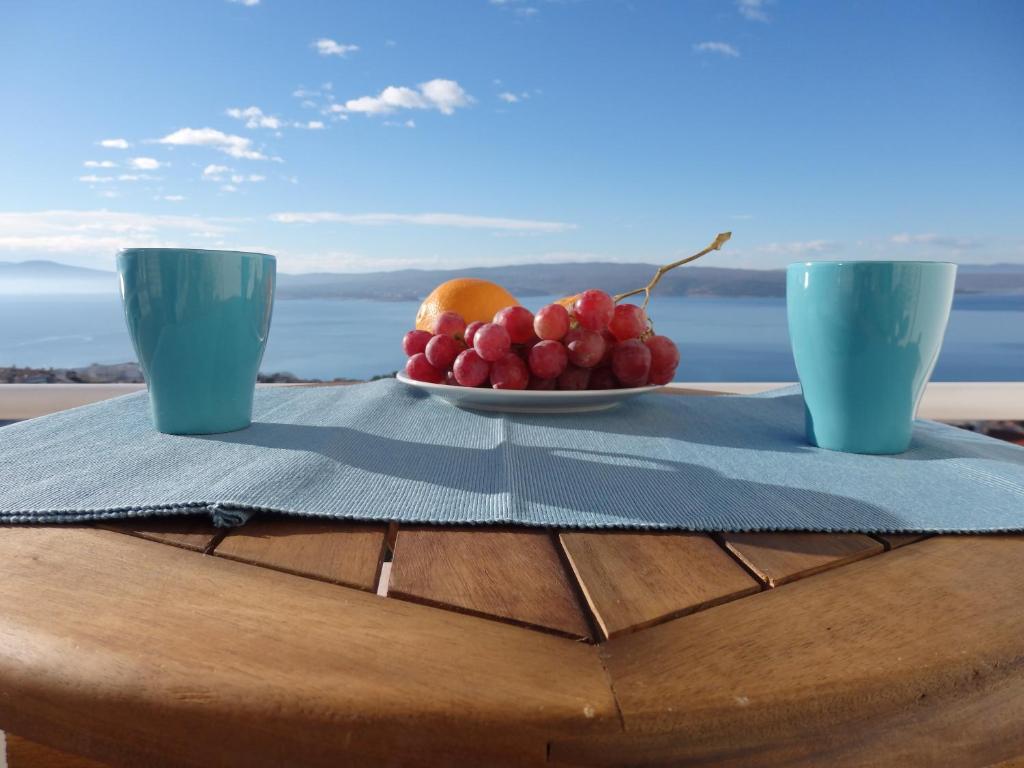 a plate of fruit on a table with two cups at Aspectus Apartment in Crikvenica