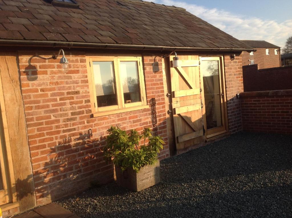 a brick house with a door and a potted plant at ANVIL COTTAGE in Whitchurch