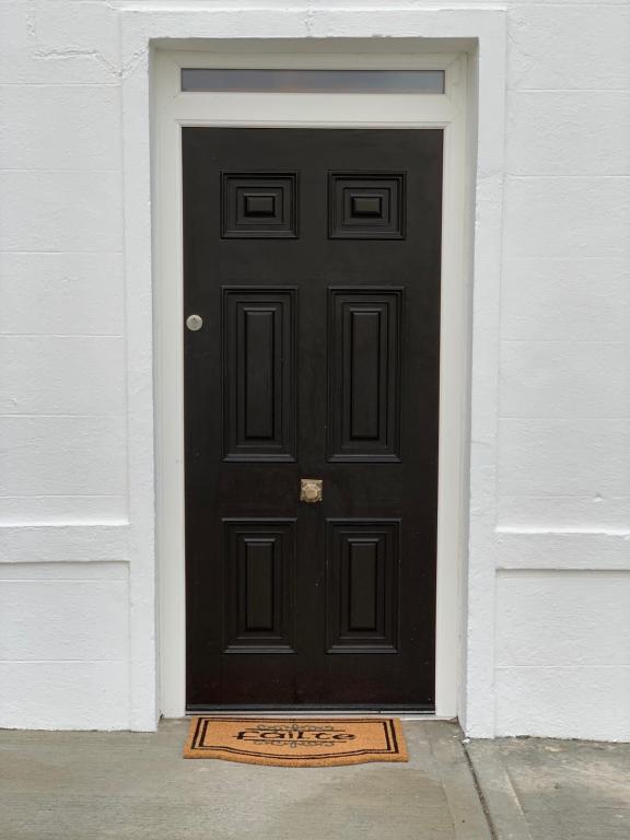 a black door with a welcome mat in front of it at Biddy Ban’s in Carnmalin