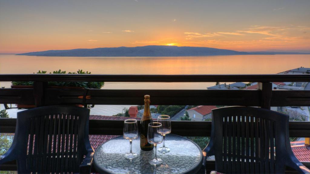 a table with two wine glasses on a balcony with a sunset at Apartment Lea in Senj