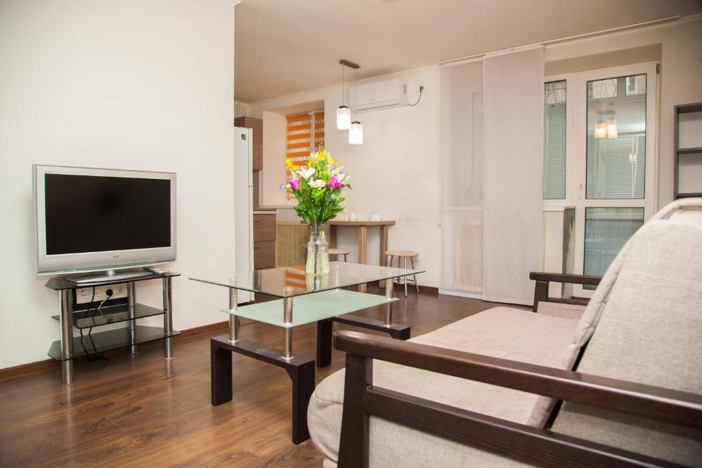a living room with a television and a vase of flowers at Semi-luxury Apt on Ukrainskaya 43 Street in Zaporozhye