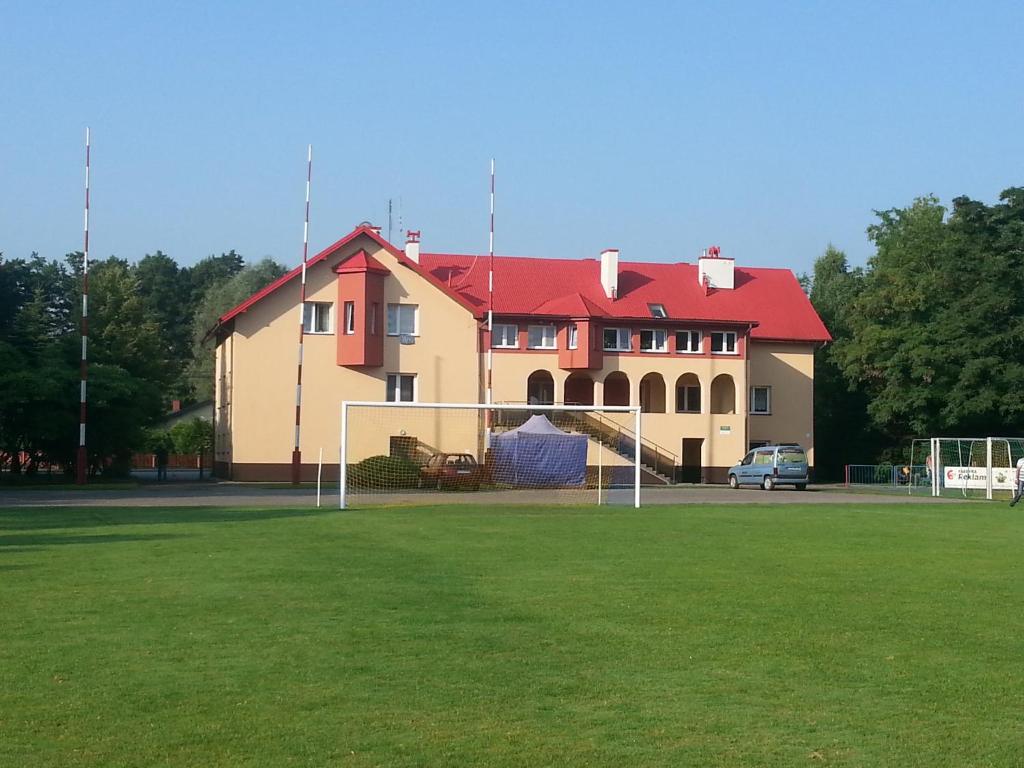 a large building with a red roof and a soccer field at Ośrodek Sportowo Wypoczynkowy PUSTYNIA in Dębica