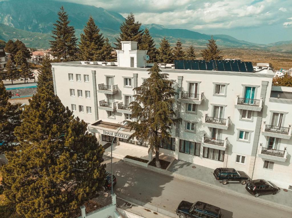 a large white building with cars parked in front of it at Hotel Turizem Shkelzeni in Kolgecaj