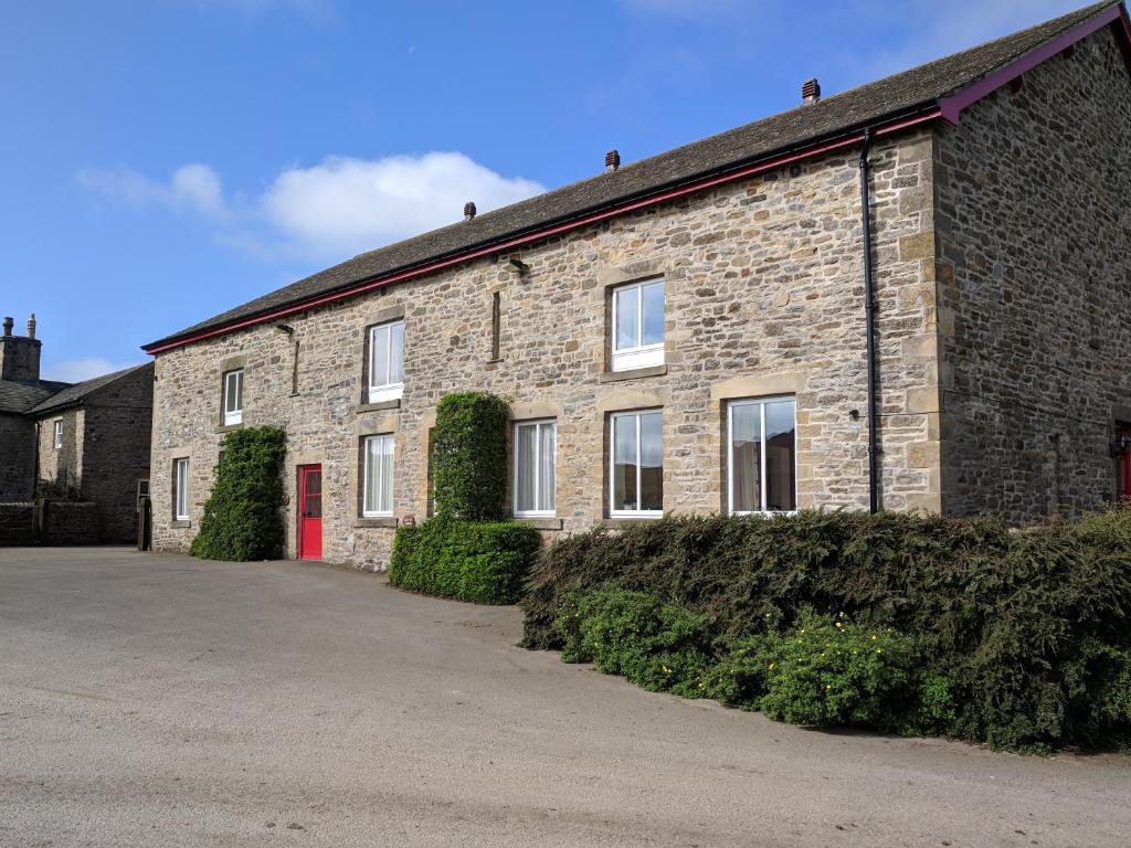 a brick building with a red door on a street at Mellwaters Barn Cottages in Bowes