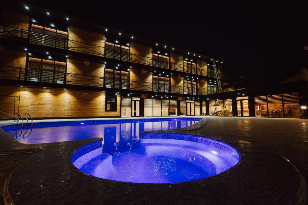 duży budynek z niebieskim basenem przed nim w obiekcie Barhat Resort w mieście Taraz