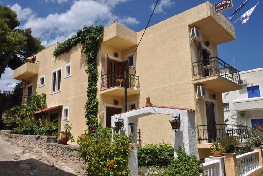 a large yellow building with ivy on it at Artemis Rooms in Agia Marina Aegina