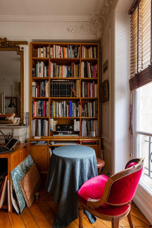 a room with a table and a book shelf with books at Veeve - Artistic in Pigalle in Paris