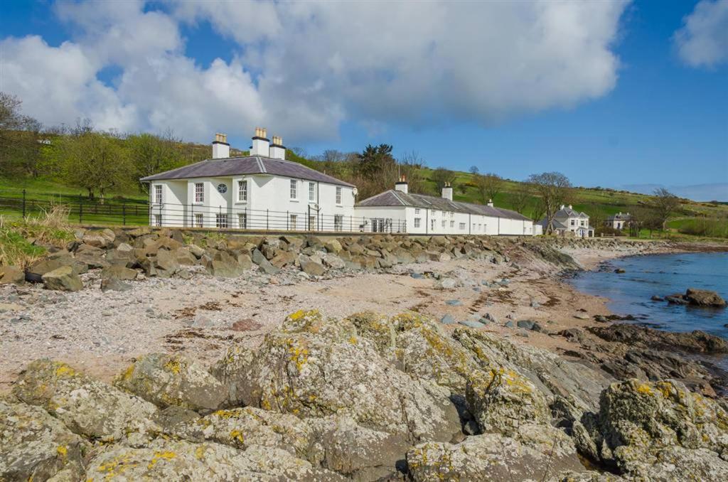 a white house on the shore of a beach at Rockport Lodge in Cushendun