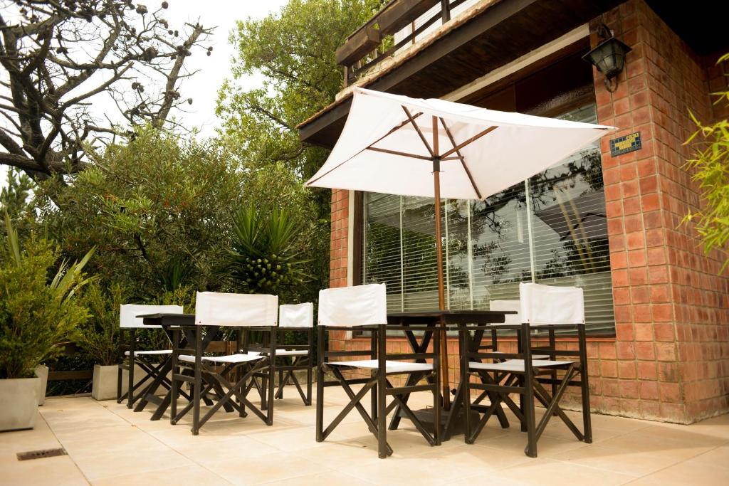 una mesa negra con sillas blancas y sombrilla en Hosteria Costa Blava en Villa Gesell