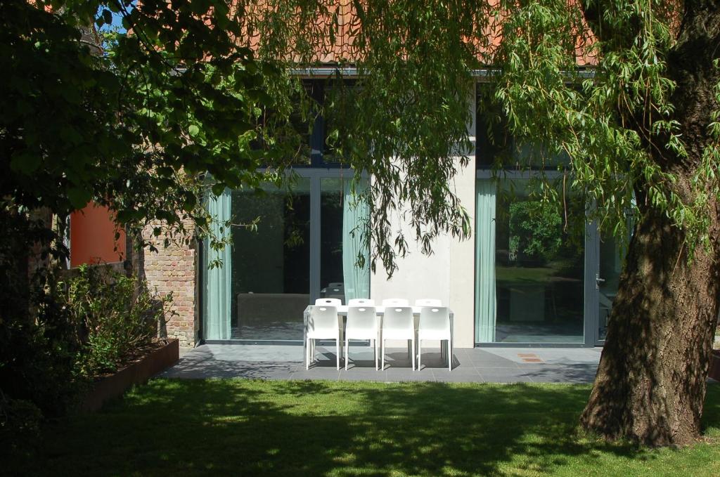 3 chaises blanches assises devant un bâtiment dans l'établissement Het Wagenhuis, à Lo-Reninge