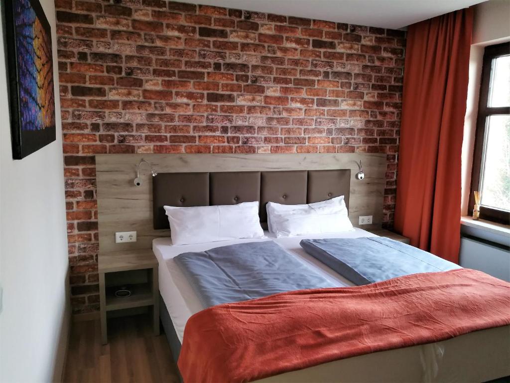 Bett in einem Zimmer mit Ziegelwand in der Unterkunft Landhotel Römerkessel in Landsberg am Lech