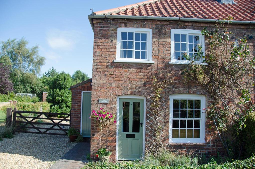 a brick house with a green door and windows at 1 Hope Cottage in Spilsby
