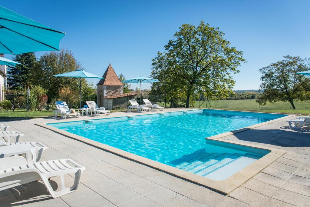 a swimming pool with chairs and umbrellas in a yard at Bruet Gites in Yviers