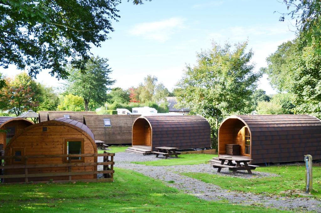 un grupo de cabañas en un parque con un banco en Woodclose Park en Kirkby Lonsdale