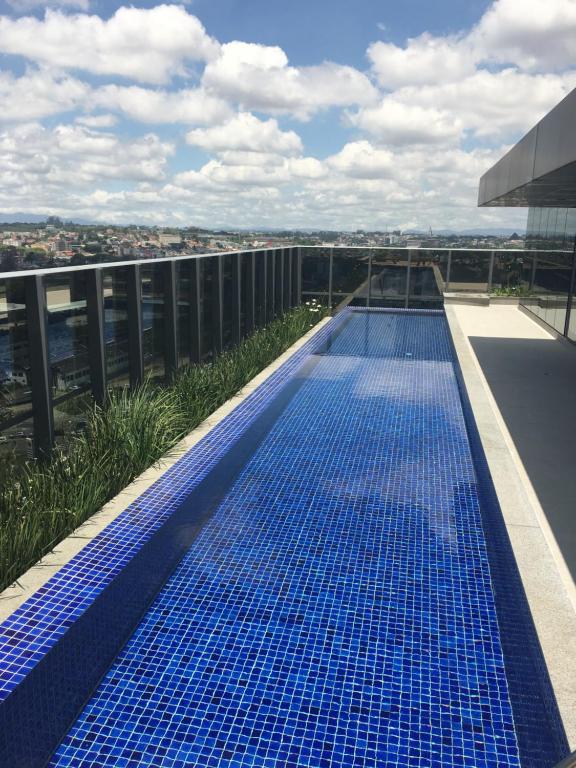 una piscina azul en la azotea de un edificio en Estudio moderno com linda vista para a Serra en Curitiba
