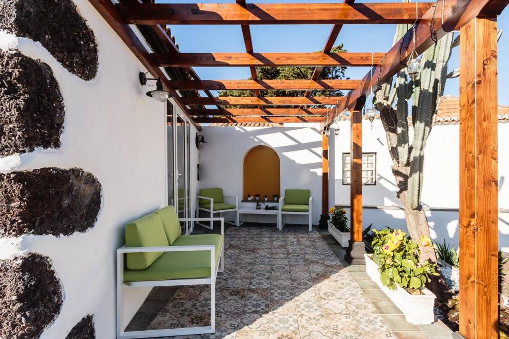 a patio with green chairs and a wooden pergola at Bungalow Los Laureles in El Paso