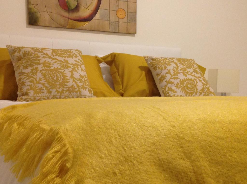 a bed with a yellow blanket and pillows on it at B&B Campesio al2 in Piacenza