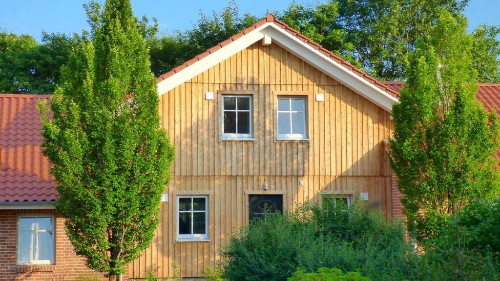 une maison en bois avec deux arbres devant elle dans l'établissement Fewo-Mundi, à Egestorf