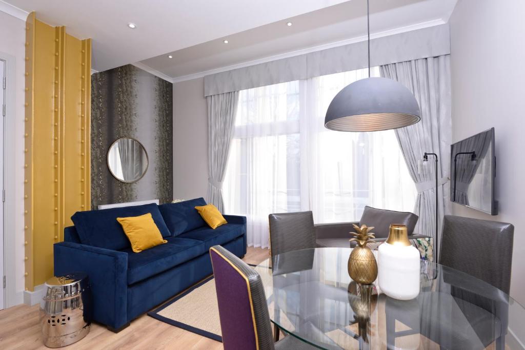 a living room with a blue couch and a glass table at Destiny Scotland Charlotte Square Apartments in Edinburgh