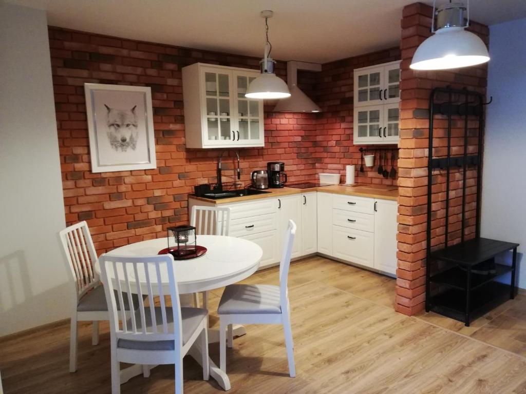 uma cozinha com uma mesa e cadeiras e uma parede de tijolos em Apartament Uśmiech em Ustrzyki Dolne