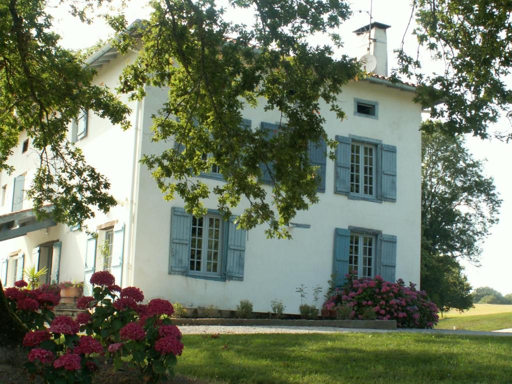 een wit huis met blauwe luiken en bloemen bij BIDACHUNA in Saint-Pée-sur-Nivelle