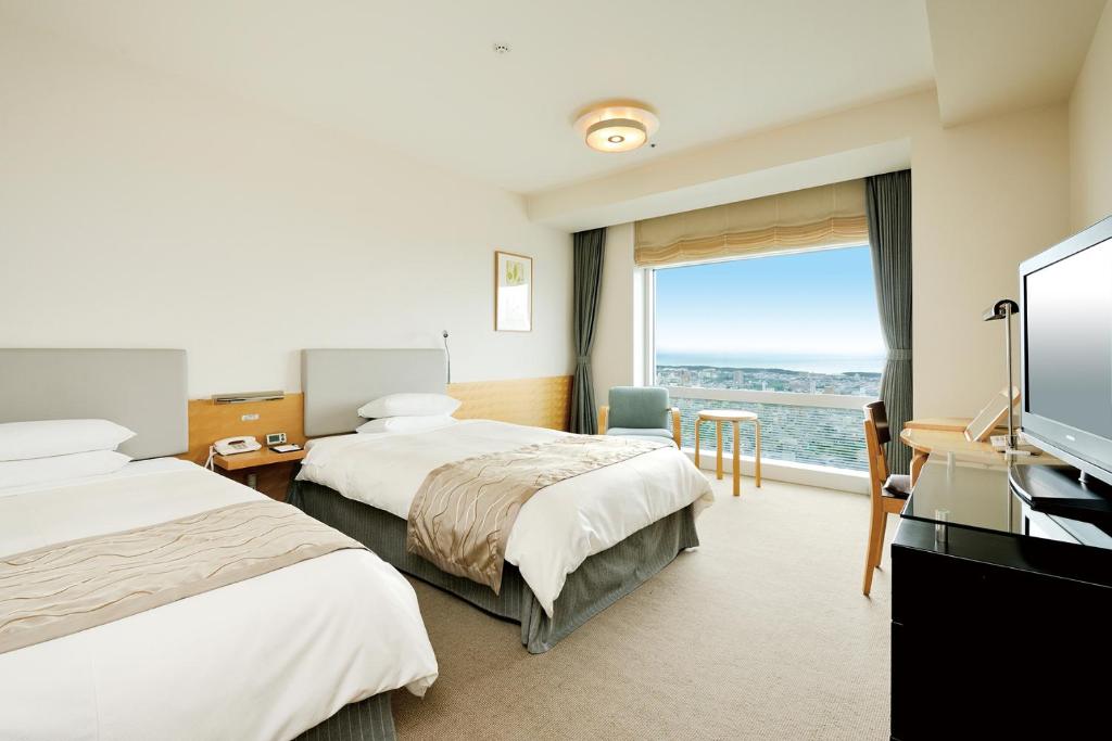 a hotel room with two beds and a flat screen tv at Hotel Nikko Niigata in Niigata