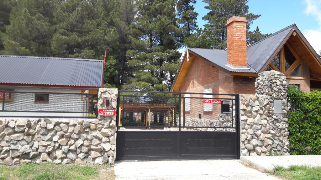 a house with a black garage door and a stone wall at Cabañas Pyracantha in Esquel