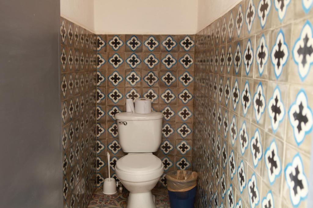a bathroom with a toilet in a tiled wall at Hostal La Tortuga Booluda in León