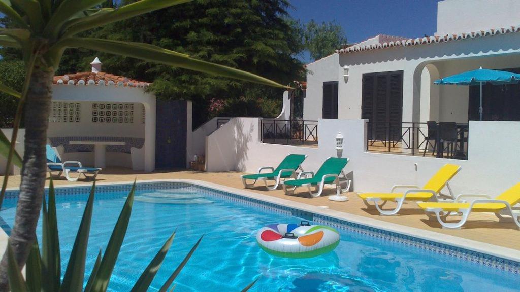 a swimming pool with chairs and a ball in it at Casa Esperanca in Carvoeiro