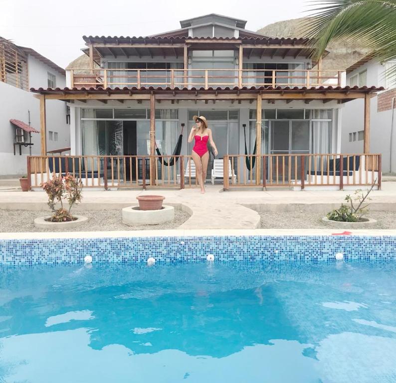 una mujer en bikini parada frente a una casa en Punta Sal Vista Hermosa, en Canoas de Punta Sal