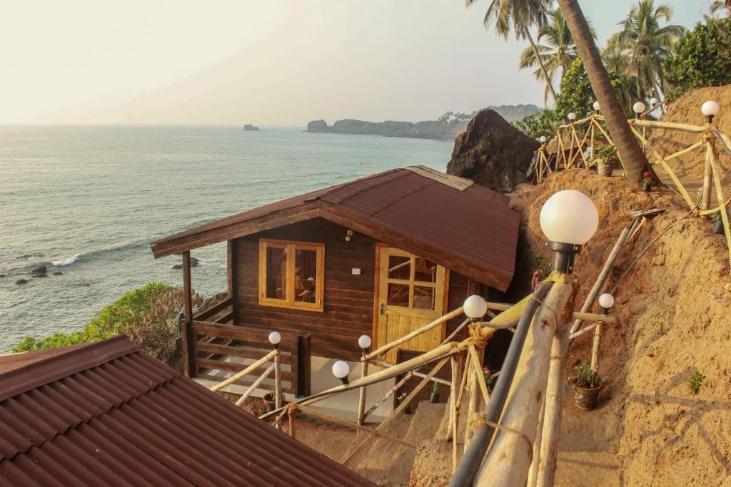 a small house on a cliff next to the ocean at Red Crab Eco Resort in Cabo de Rama