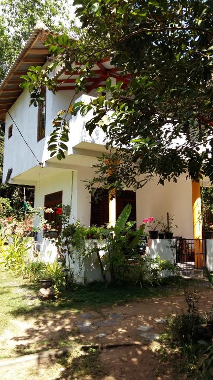 a white house with a tree in front of it at Happy Spring Guest in Mirissa