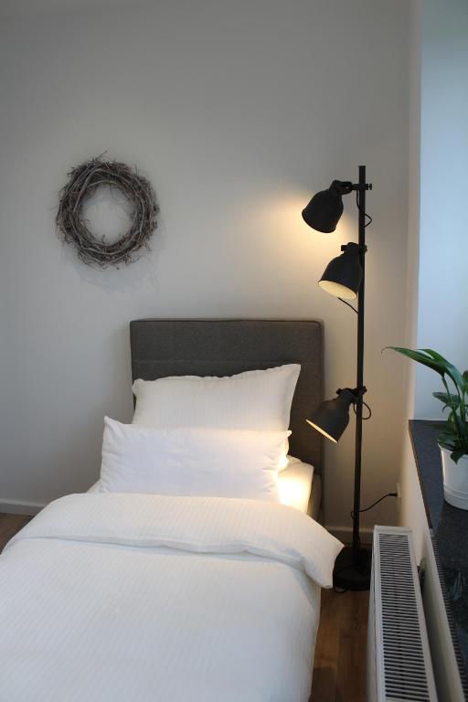 a bedroom with a white bed and a lamp at Gästezimmer Bergerhof - Ankommen und Wohlfühlen in Neuss