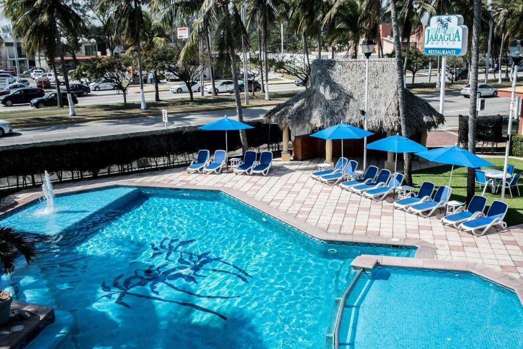 a large swimming pool with chairs and umbrellas at Hotel Jaragua in Veracruz